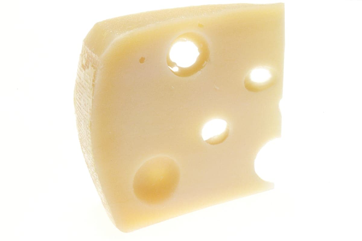 A wedge of Swiss cheese with several round holes, photographed against a white background.